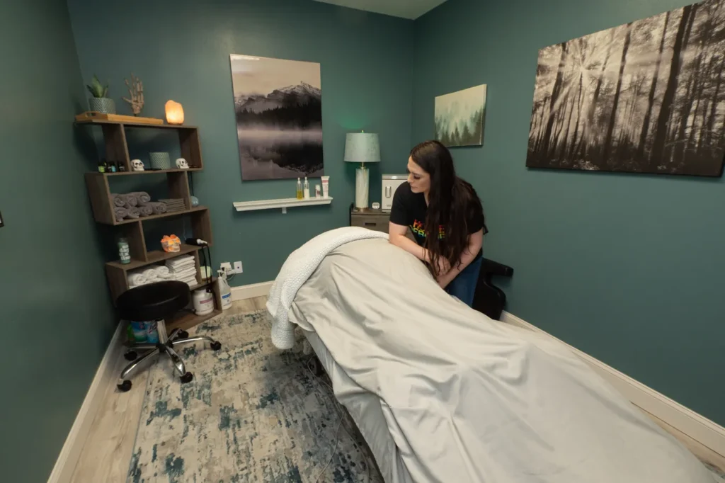 Massage therapist using elbox to massage patient under a beige blanket